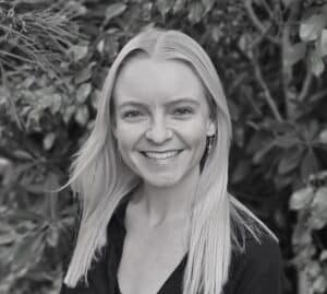 Alexi Savage, naturopath specializing in skin, stress, genitourinary health, gut issues, and anxiety, with greenery background.