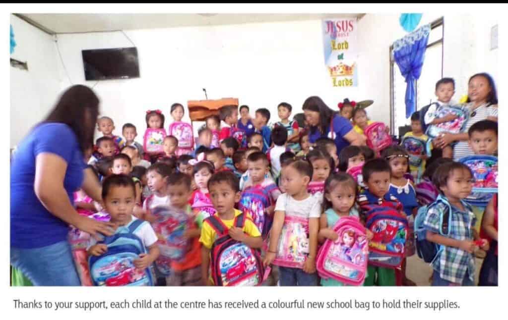 Children at a sponsorship center in the Philippines, each holding colorful school bags, celebrating educational support and community engagement through the Integrated Wellness Clinic's charitable initiatives.