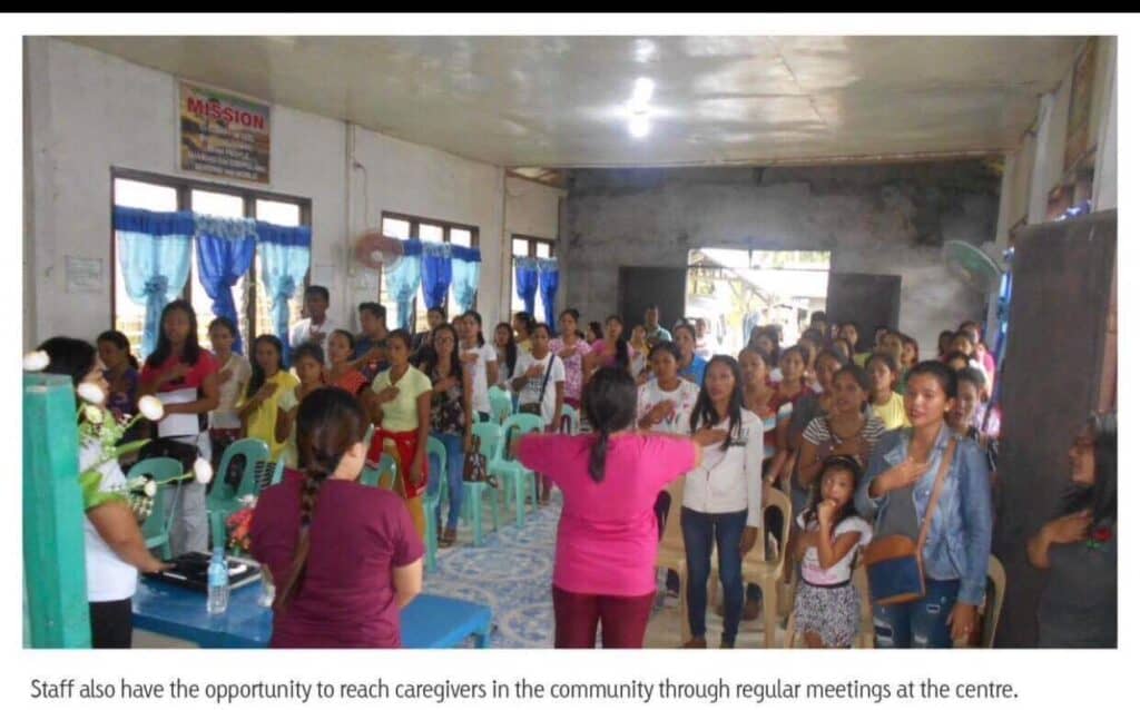 Community meeting at Compassion Sponsorship Centre in the Philippines, with caregivers engaging in discussion and support activities, emphasizing collaboration and health education for vulnerable families.