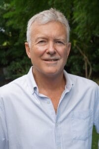 Psychologist Ambrose McKinnery from Integrated Wellness Clinic, smiling in a natural outdoor setting, promoting relationship counselling services.