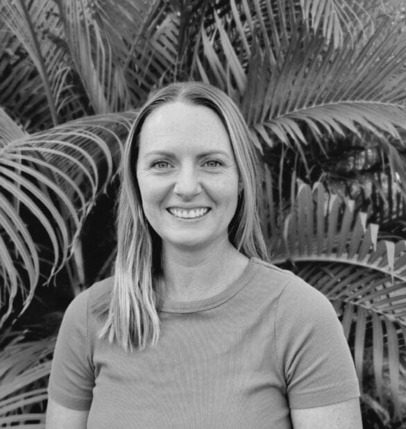 Hannah Powter, Accredited Practising Dietitian, smiling in front of tropical foliage, promoting holistic nutrition and health services.