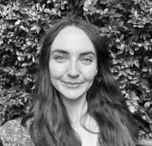 Arabella Richards, Integrative Naturopath, smiling in front of green foliage, emphasizing holistic health and personalized care in women's health and wellness.