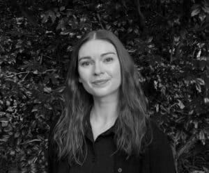 Brisbane educational and developmental psychologist Ebony Matthews smiling in front of greenery, representing child psychology services at Integrated Wellness Clinic.