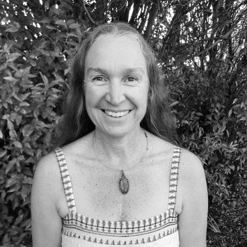 Smiling woman with long hair wearing a patterned dress, standing in a natural setting, representing the holistic approach of Integrated Wellness Clinic's naturopathy services.