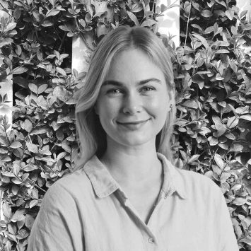 Brianna Thompson, naturopath at Integrated Wellness Clinic, smiling against a backdrop of greenery, specializing in gut health, mental health, and women's health.