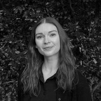 Educational and Behavioural Psychologist Ebony Matthews, smiling in front of greenery, offering autism assessments for ages 5-18 at Integrated Wellness Clinic in Brisbane.
